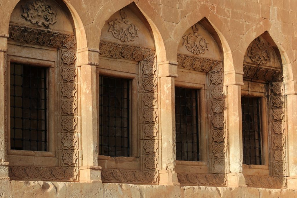 Close-up of historic building windows with intricate stone carvings, showcasing architectural beauty.